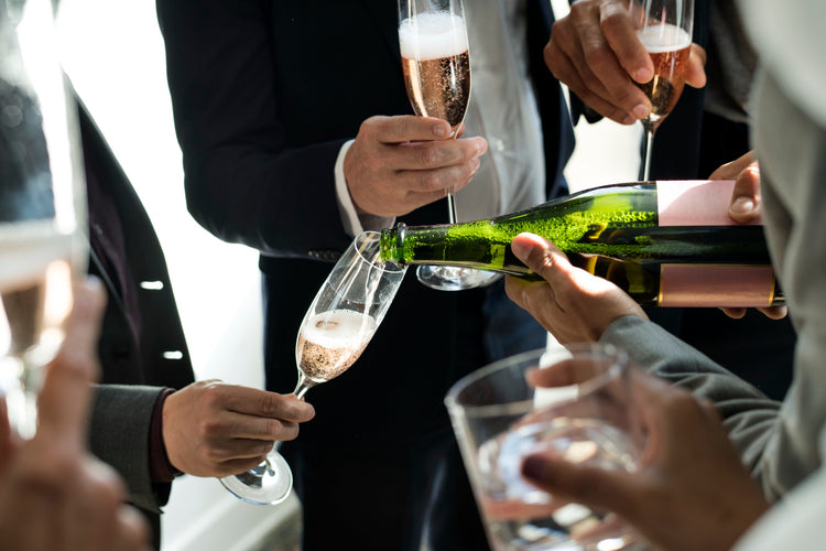 Rosé Champagne poured into a flute among guests holding glasses